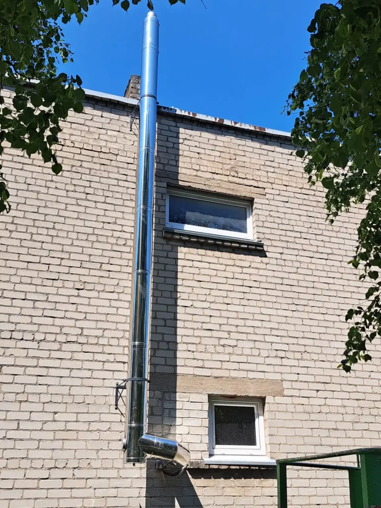 Namo siena su mažu langu ir matomu stulpu.