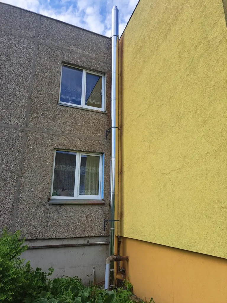 Geltonos sienos ir balto lango stambus planas. Langas turi baltą rėmą ir yra padalintas į mažesnius kvadratus.